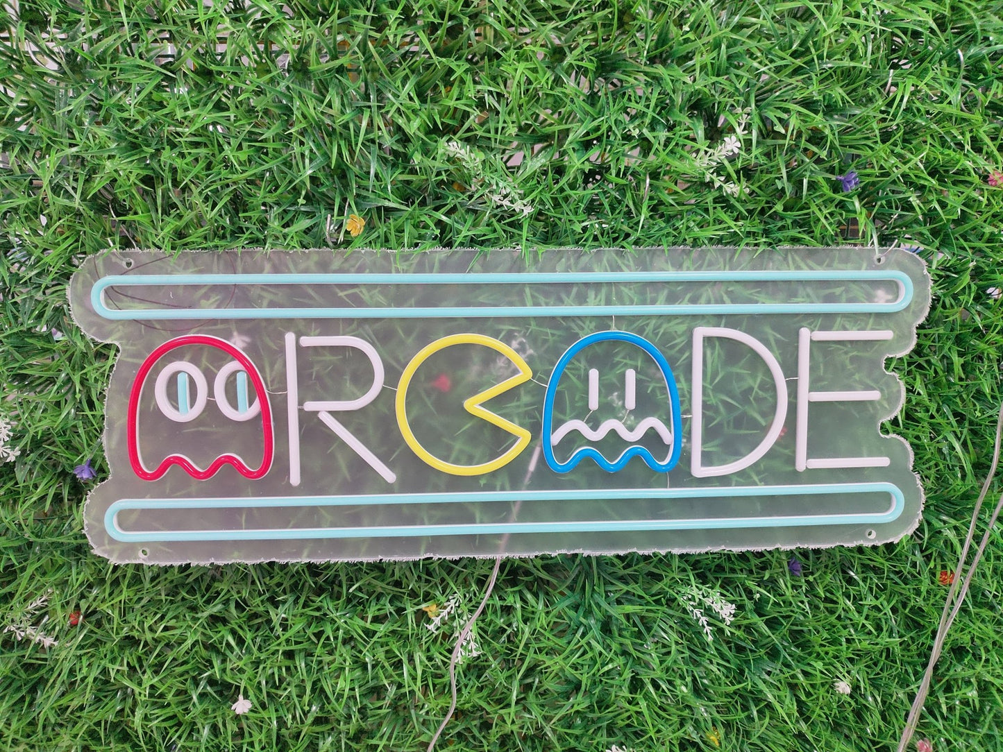 Arcade neon sign switched off showing retro pixel-style gaming design with ghost characters on clear acrylic panel