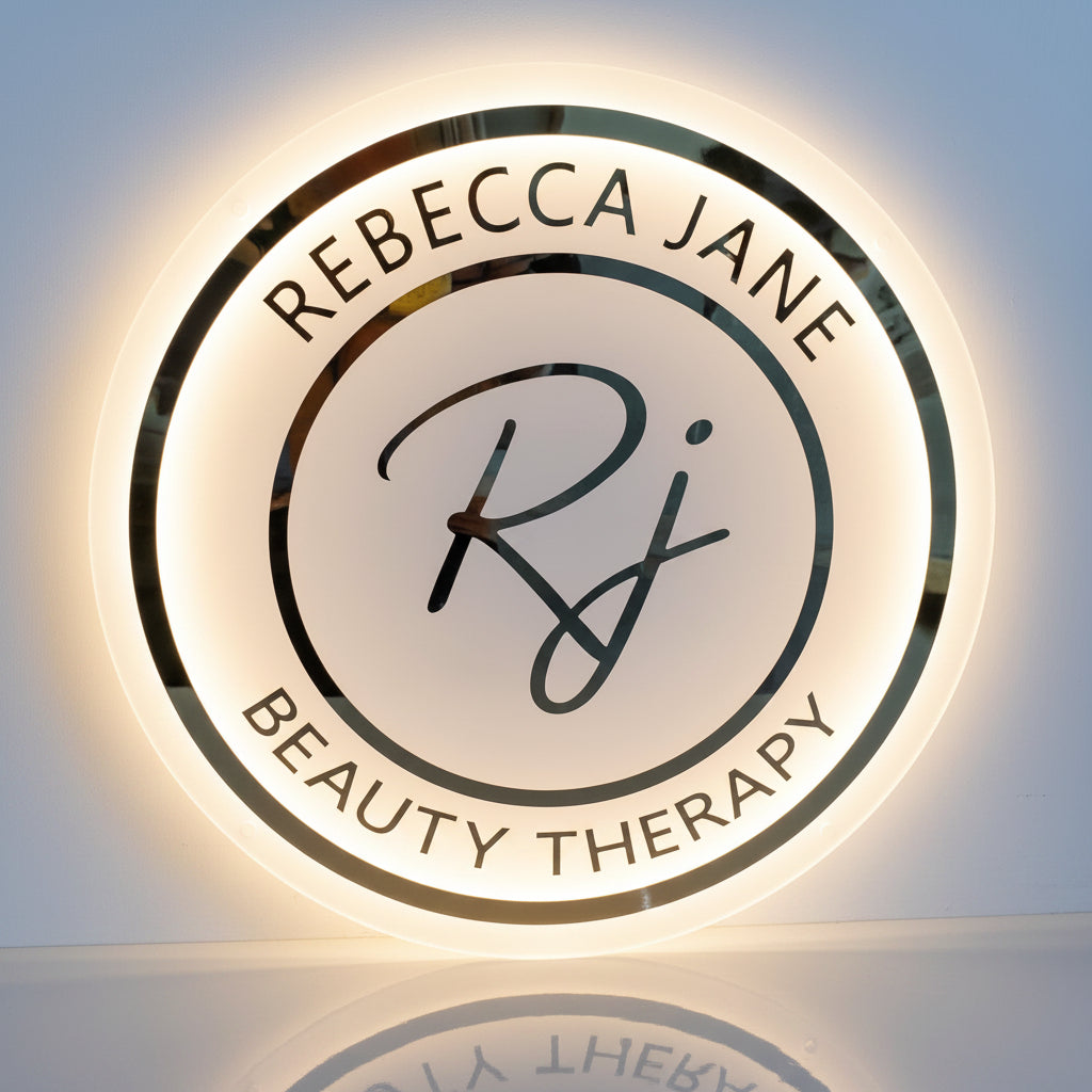 Round backlit acrylic sign with mirror gold logo for Rebecca Jane Beauty Therapy in Sale, Greater Manchester, warm white LED halo glow