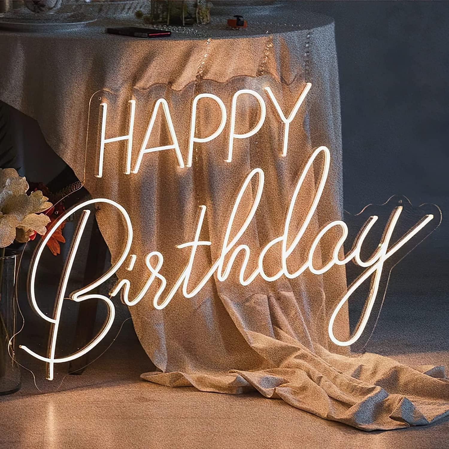Happy Birthday neon sign in LED flex with clear acrylic backing, featuring block and script lettering – displayed indoors against draped fabric.