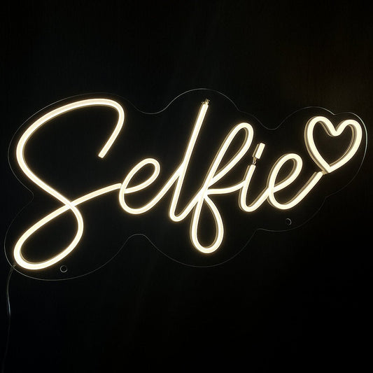 Selfie neon sign with heart in warm white LED flex and cut-to-shape acrylic backing on black background – perfect for salons, bars, and photo walls