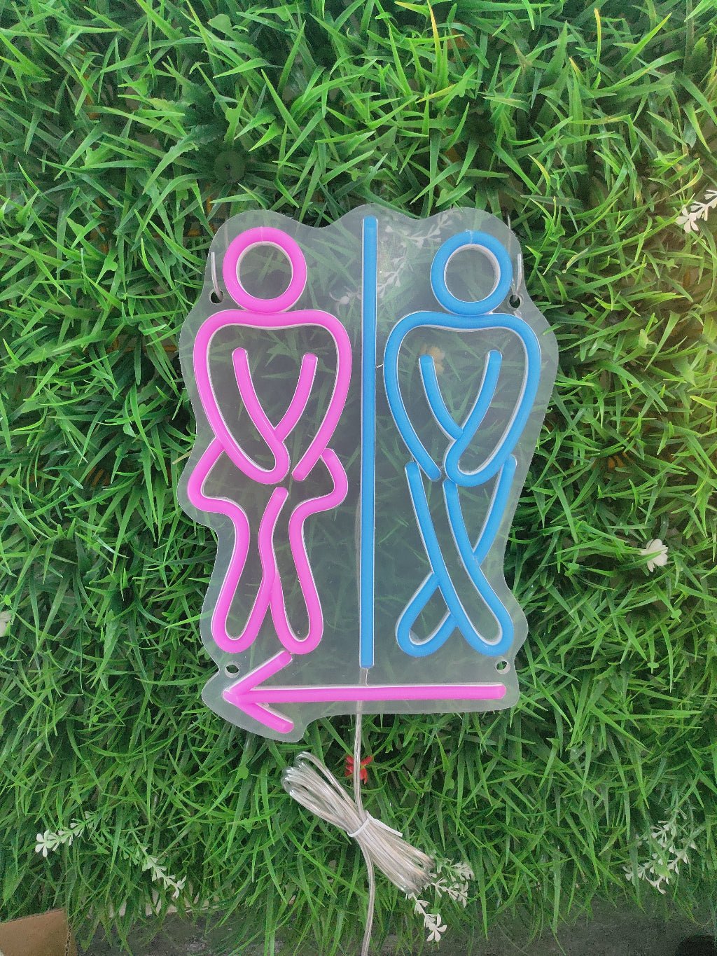 Toilet neon sign switched off showing pink and blue restroom figures with arrow on clear acrylic backing