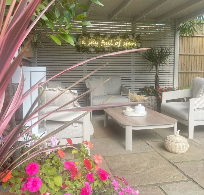 Warm white LED neon sign reading a sky full of stars on garden bar outdoor seating area with wooden slatted wall backdrop UK