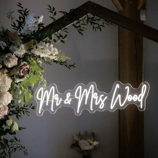 Mr and Mrs Wood custom wedding neon sign hanging on floral arch backdrop