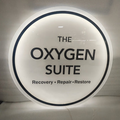 Circular backlit LED logo sign for The Oxygen Suite therapy and fitness clinic, illuminated acrylic business sign with halo glow