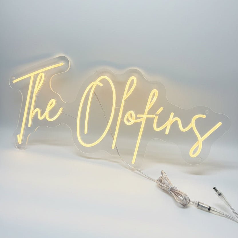Bespoke last name wedding neon sign spelling out The Olofins in a bright script font with clear acrylic backing.