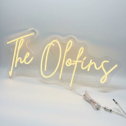 Bespoke last name wedding neon sign spelling out The Olofins in a bright script font with clear acrylic backing.