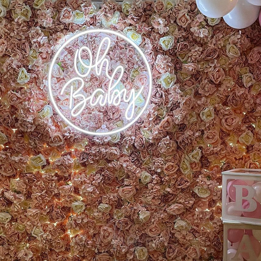 Custom script FlexNeon sign 'Oh Baby' mounted on a pink floral event wall, showcasing a logo to LED neon transformation for parties and celebrations.