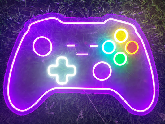 Gamepad gaming controller neon sign illuminated with multicolour LED showing buttons and d-pad on purple pink acrylic backing