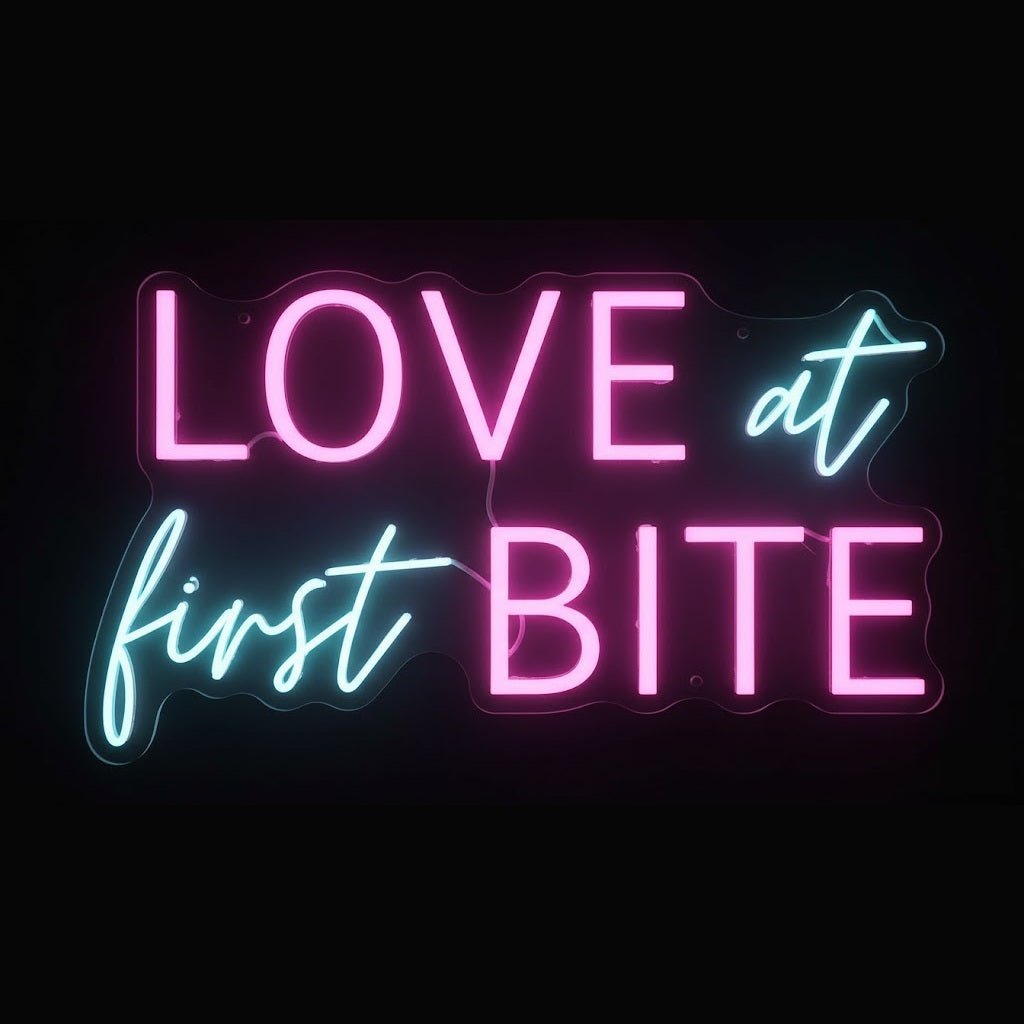 Love at First Bite neon sign in pink and blue LED flex on cut-to-shape clear acrylic backing with black background – ideal for cafés and dessert bars.
