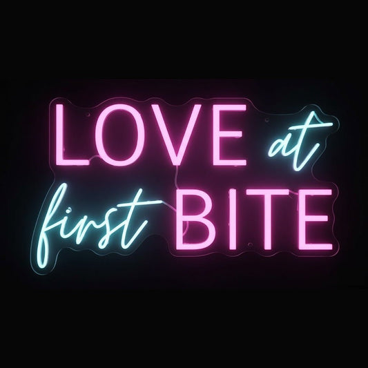 Love at First Bite neon sign in pink and blue LED flex on cut-to-shape clear acrylic backing with black background – ideal for cafés and dessert bars.