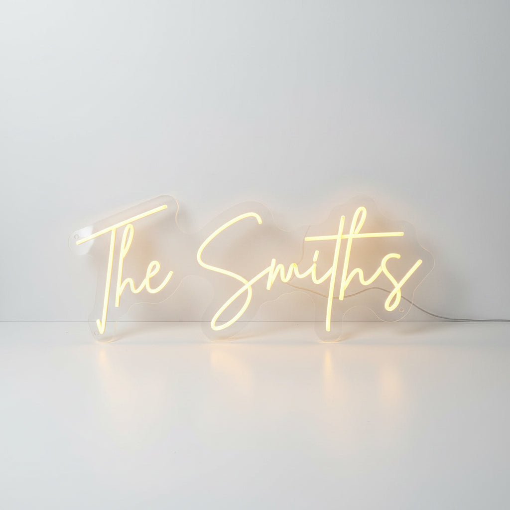 Personalised surname wedding neon sign displaying The Smiths in a warm white script font, designed by UV Neon in Manchester.
