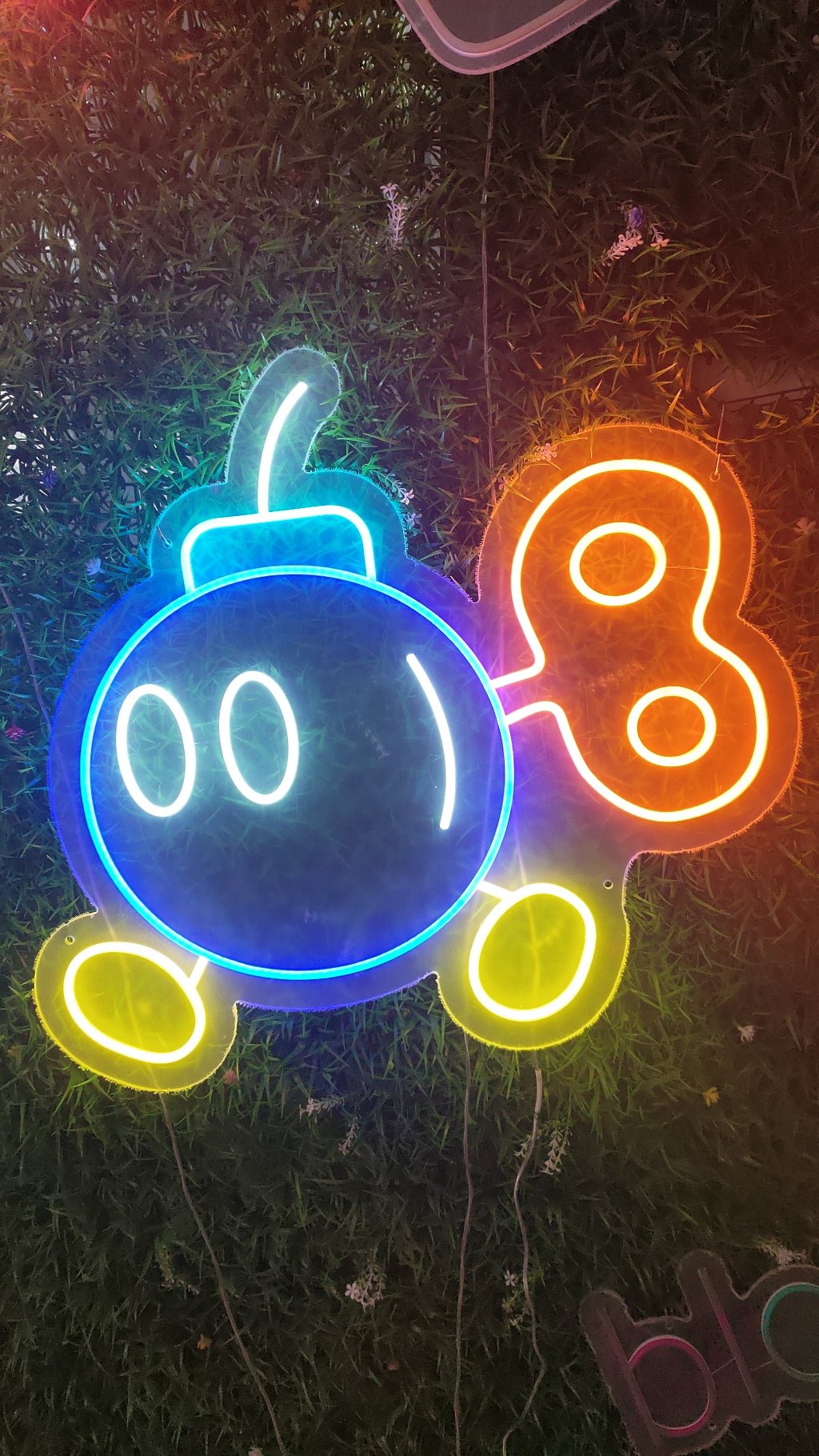 Retro pixel bomb neon sign illuminated with multicolour LED showing cartoon bomb design on clear acrylic backing for gaming room