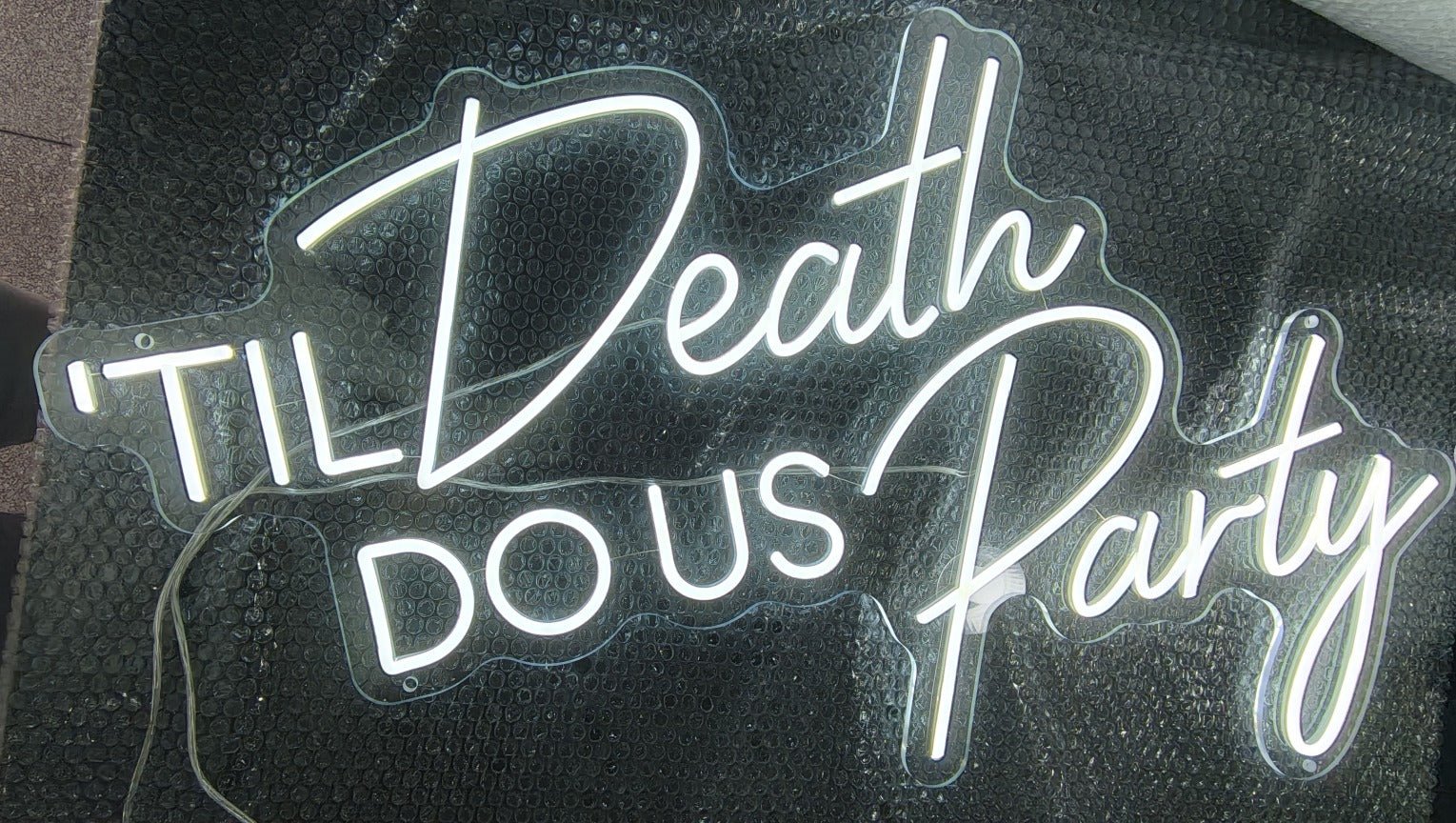 Cool white "'Til Death Do Us Party" LED neon sign in a mix of block and cursive fonts, ideal for wedding receptions and party backdrops.